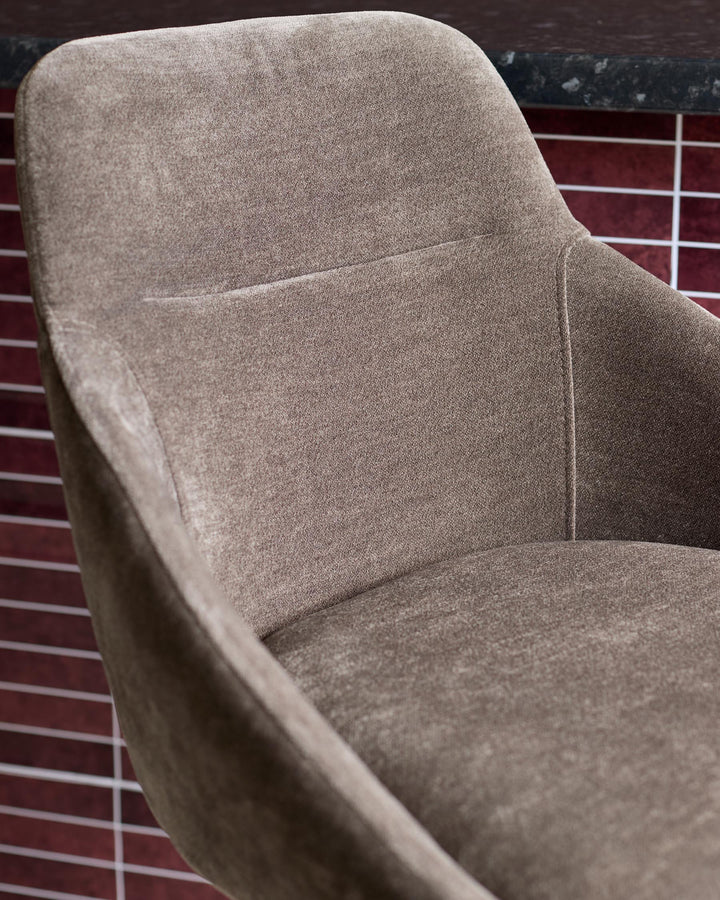 A modern, brown fabric armchair with a curved backrest and armrests, offering comfort and style.