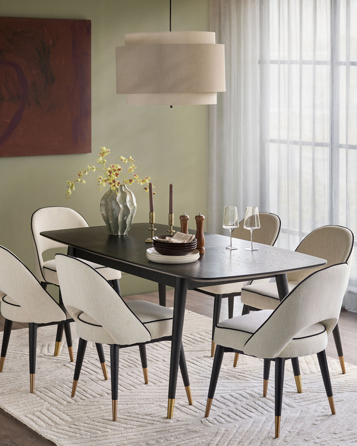 Clover ivory fabric dining chair with black legs and brass-capped feet, shown in a styled dining room setting.