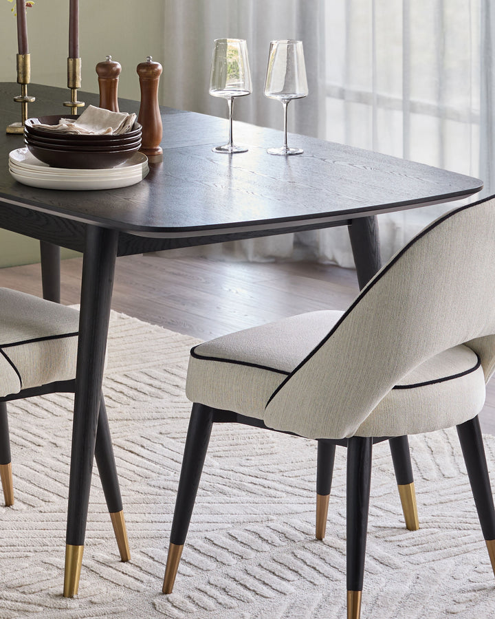 Clover ivory dining chair with black legs and brass feet accents, shown at dining table.