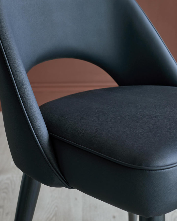 A modern, black, faux leather chair with a curved back and minimalist design, perfect for adding style to any room.