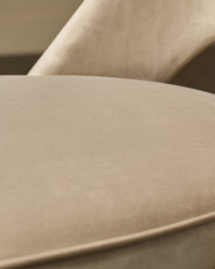 Clover velvet dining chair in champagne, close-up detail of curved seat and backrest upholstery.