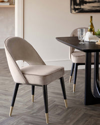 Stylish dining room with a dark wood table and two upholstered chairs with black and gold legs.
