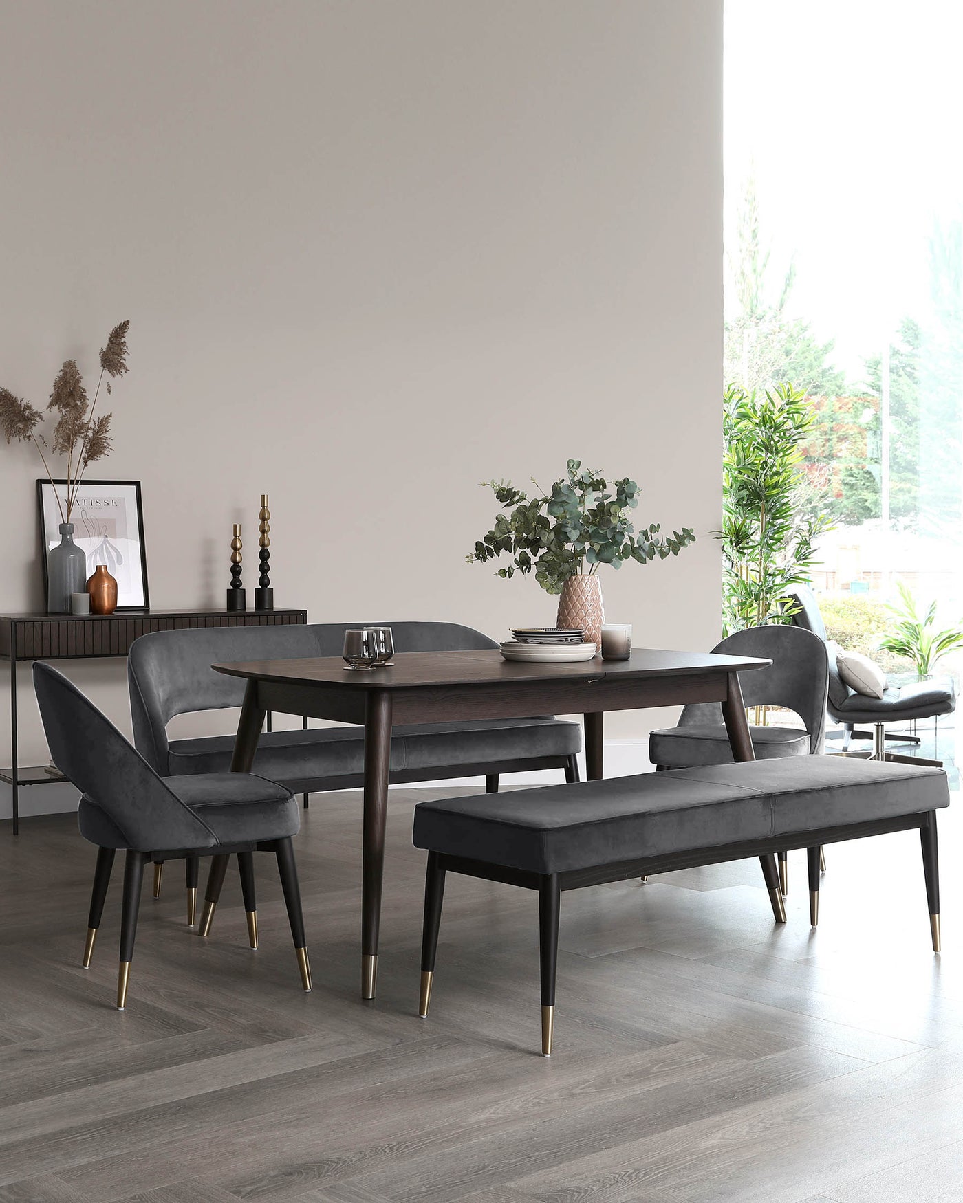 Elegant dark wood dining table complemented by a matching bench and three plush velvet chairs with brass tipped legs.