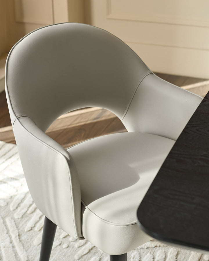 Clover dining armchair in light grey faux leather, shown from above at an angle highlighting its curved back and armrests.
