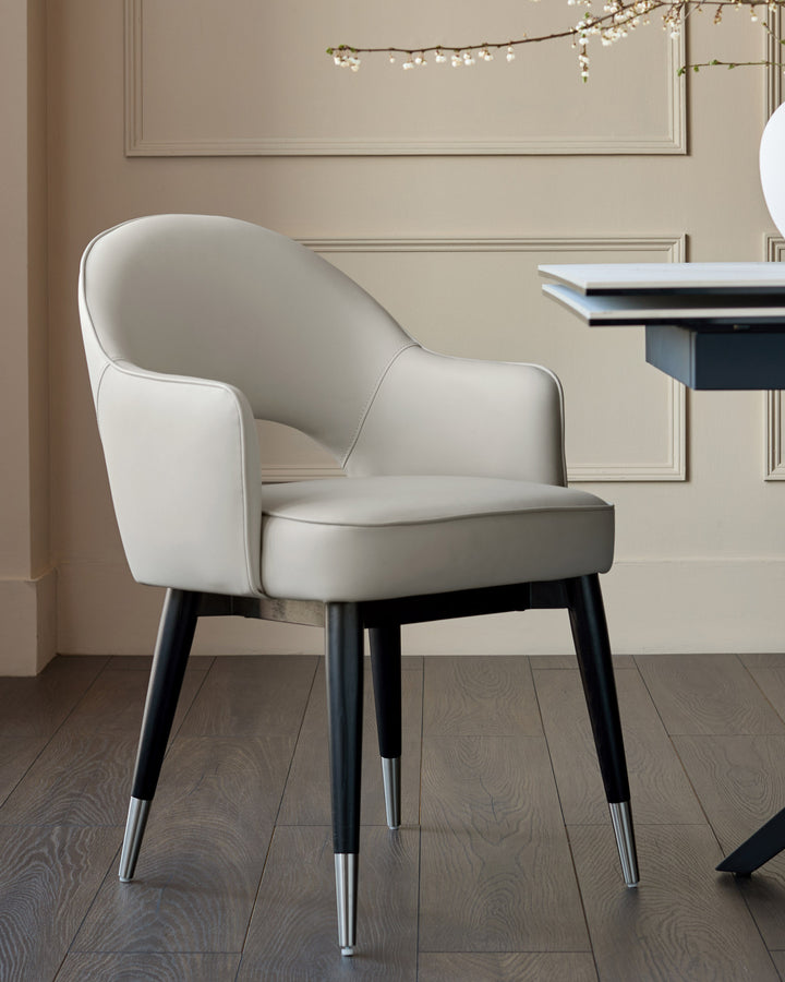 Clover dining armchair in light grey faux leather with black legs and metal foot caps, displayed in an elegant room setting.