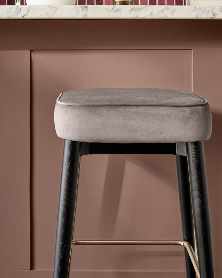 Clover velvet backless bar stool in mocha with dark wooden legs and brass footrest detail.