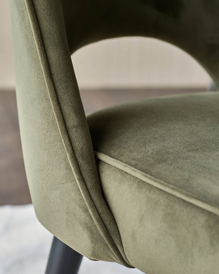 Close-up of a stylish green velvet chair with a sleek, modern design, perfect for adding a touch of elegance to any dining area.