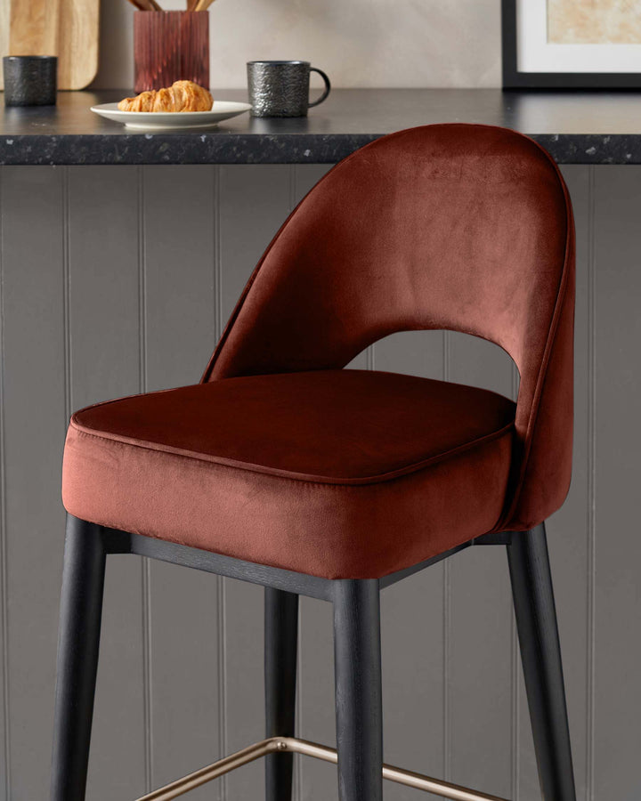 Stylish burnt orange velvet bar stool with sleek black legs and a comfortable padded seat. Ideal for modern kitchens.