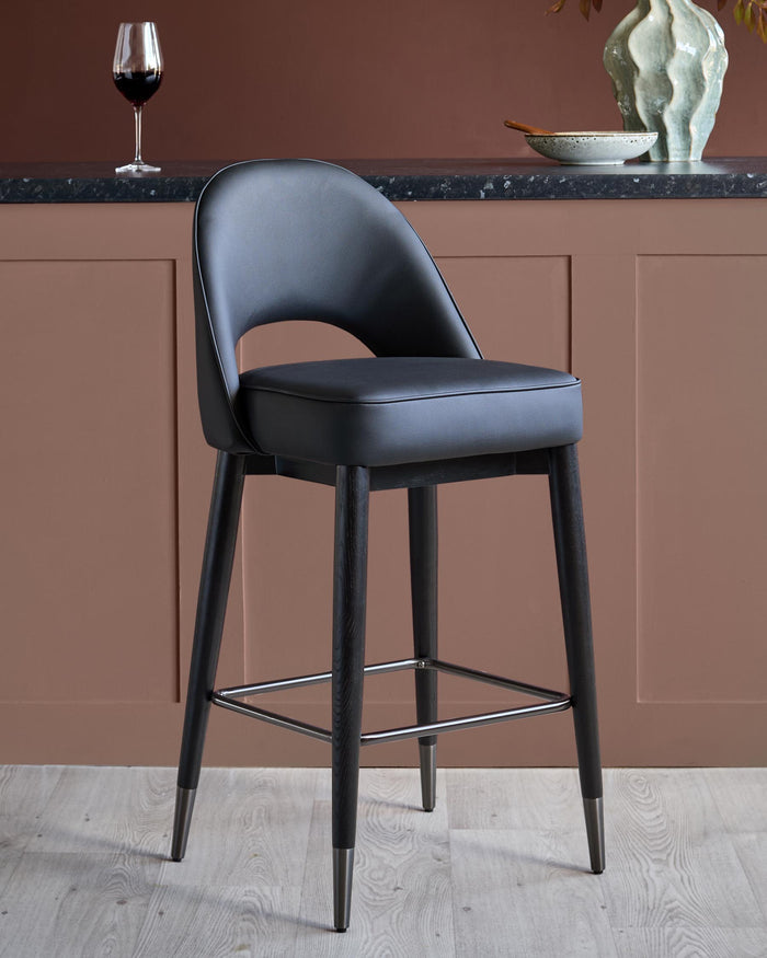A stylish black bar stool with a curved back and dark wood legs, complemented by a chrome footrest.