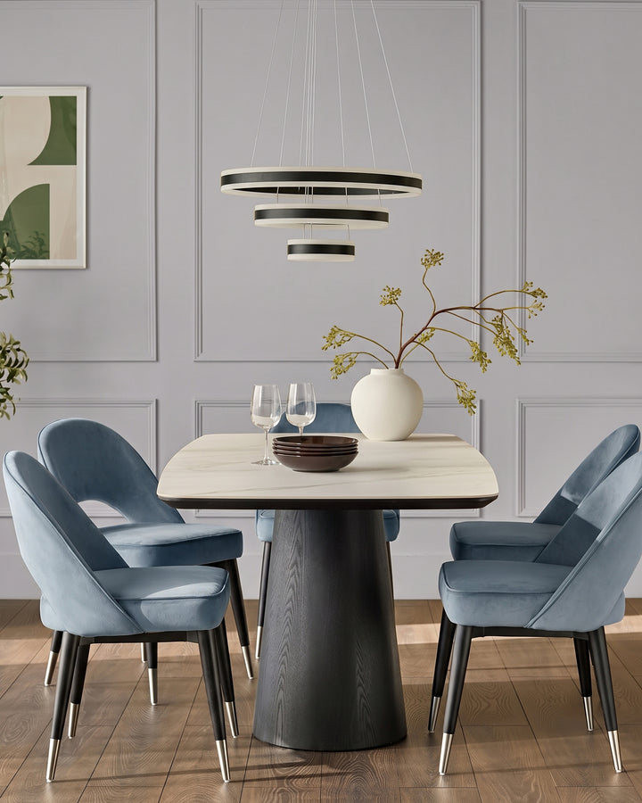 Clover velvet dining chair in blue with black legs and stainless steel caps, shown in dining room setting.