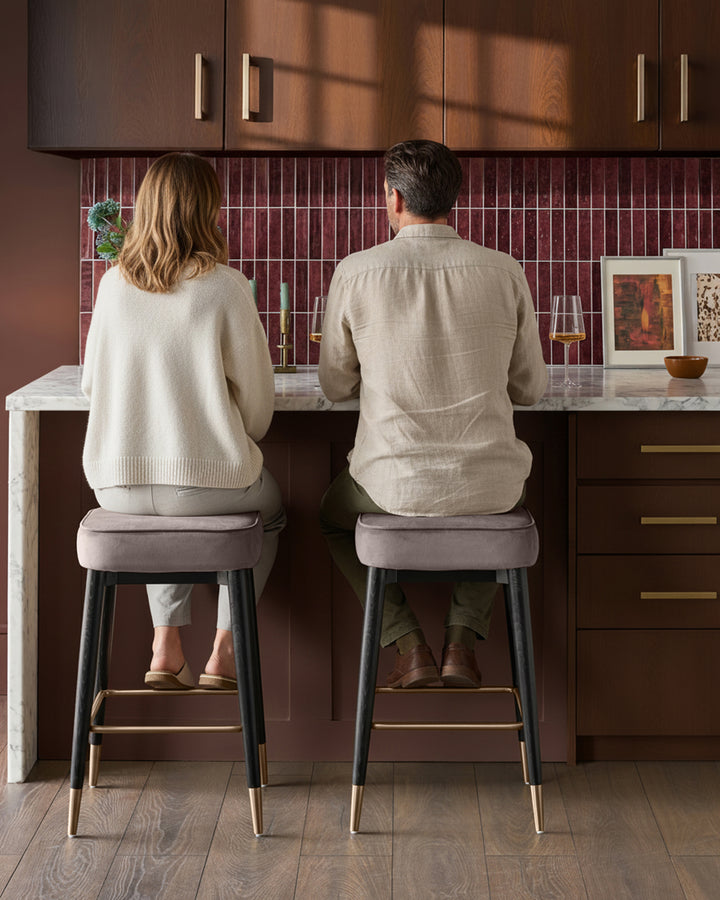 Mocha velvet backless bar stools with black legs and brass foot rails, shown in a kitchen setting.