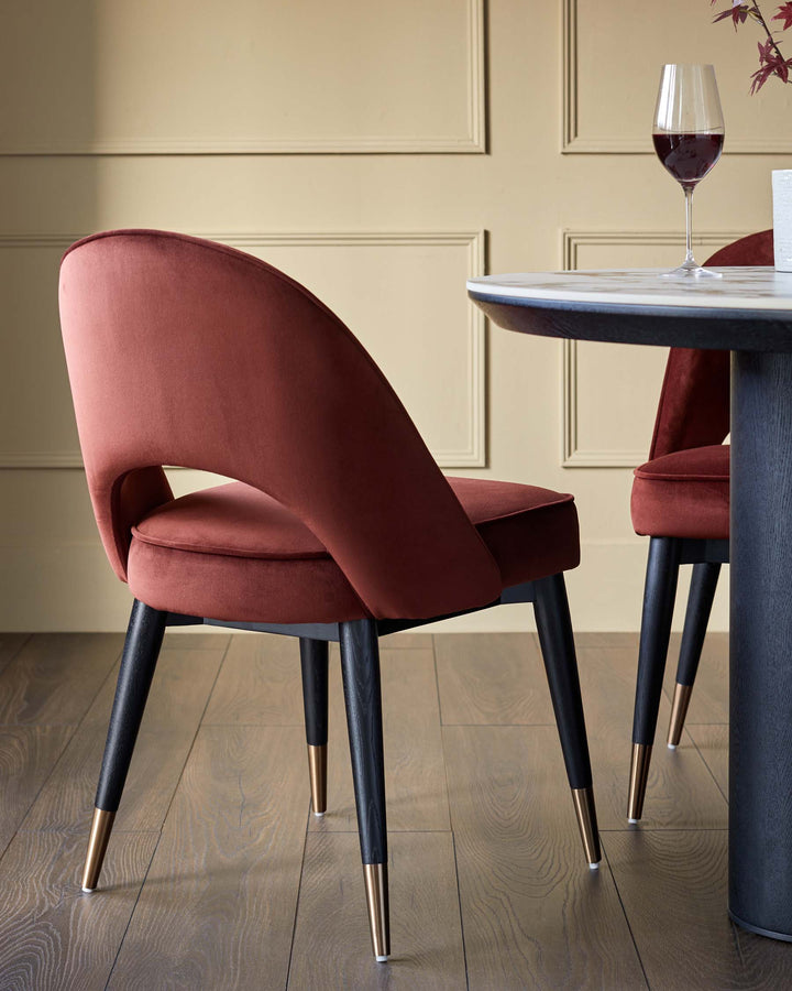 Elegant dining chairs in russet velvet with black legs & brass detailing. Stylish dining table with a marble-effect top.
