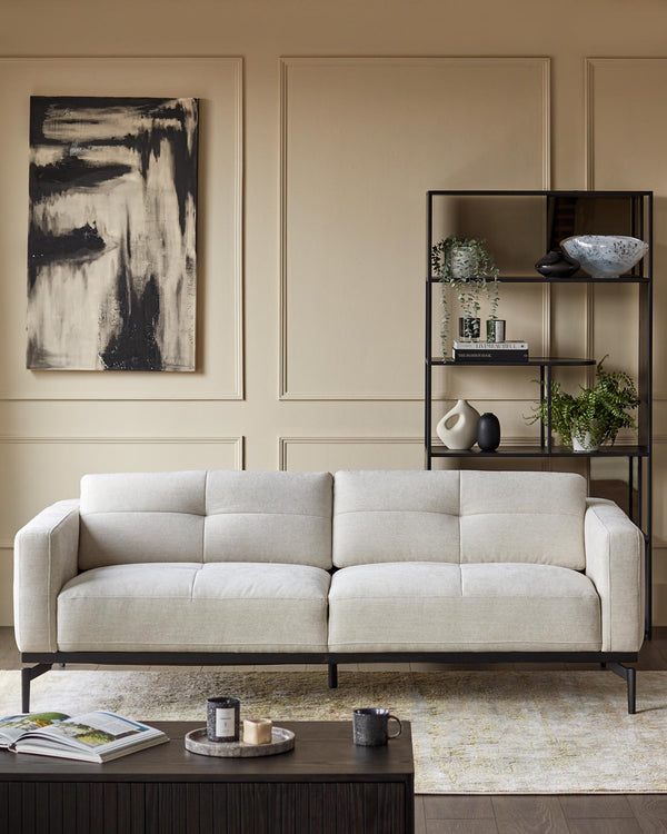 A modern living room set featuring a sofa, coffee table and display shelf with decorative items.