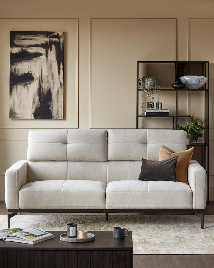 A modern living room display with a sleek sofa, dark wood coffee table and black shelving unit.