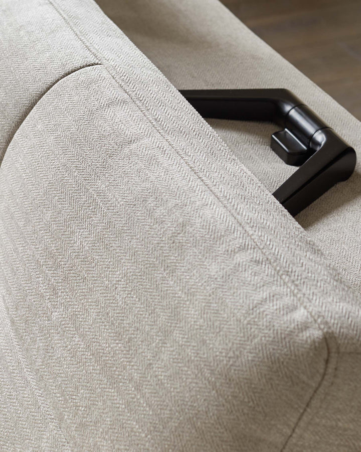Close-up of a neutral-toned sofa, showcasing its herringbone pattern and the armrest detail.