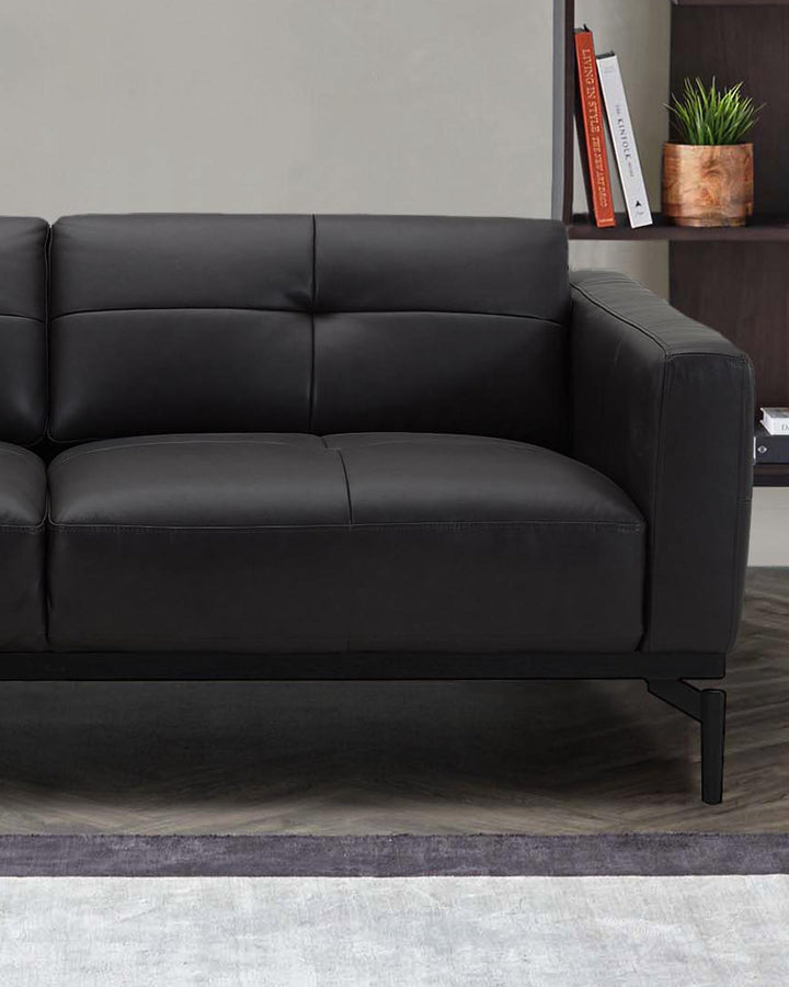 Black leather right-hand corner chaise sofa with quilted backrest and metal legs, styled in modern living room setting.