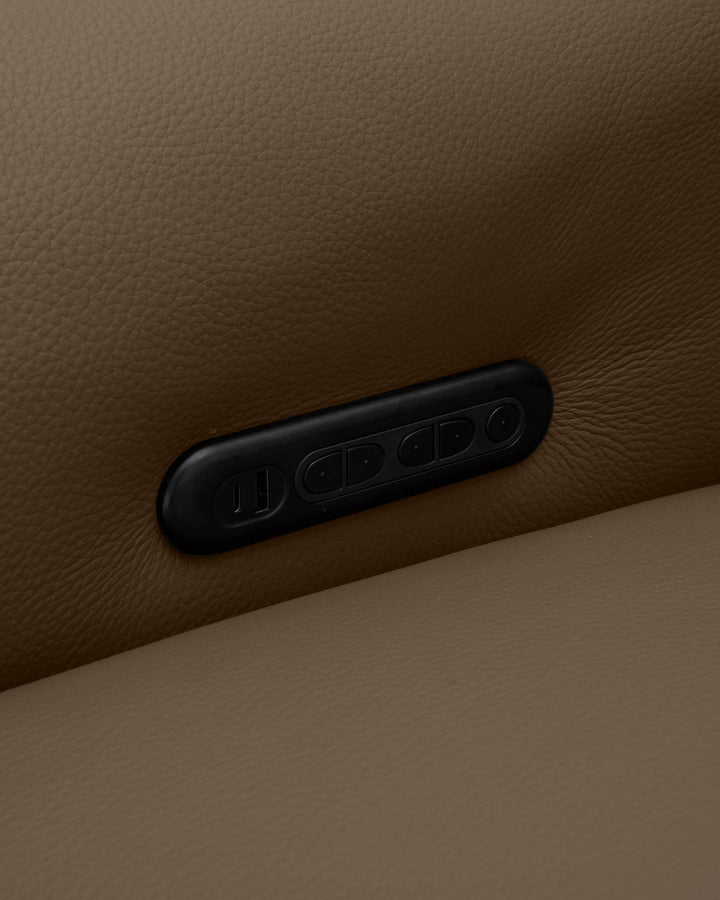 Black leather handle detail on a natural tan leather sofa arm, showing stitched design against textured upholstery.