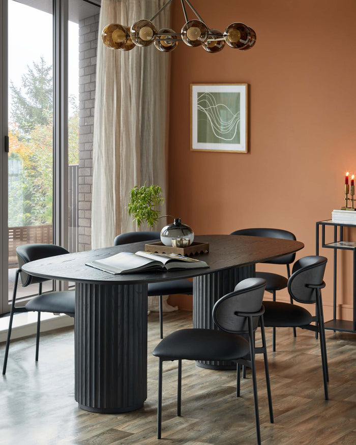 A stylish dining set with a dark wood oval table and matching black chairs, complemented by modern lighting and decor.