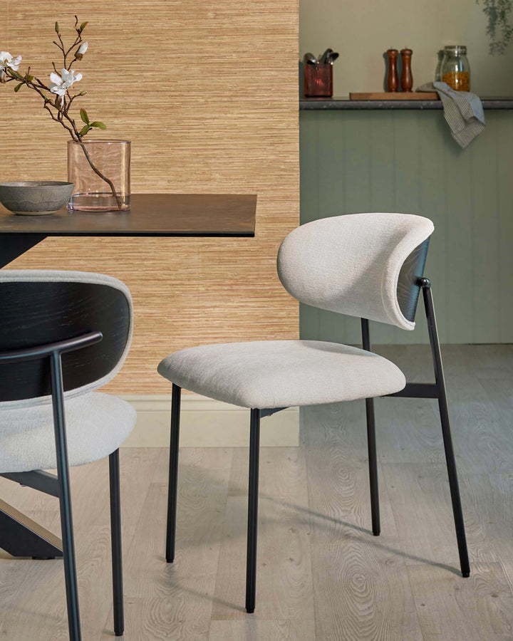 Dining area with light upholstered chairs and a dark dining table. The chairs have black frames.