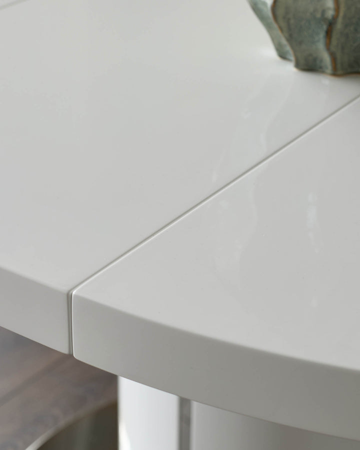 Close-up detail of white gloss round extending dining table edge and leg, showcasing smooth finish and curved design.