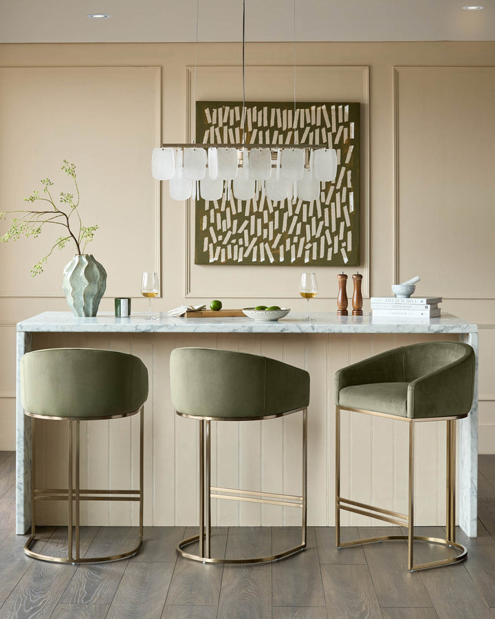 Dakota bar stool in olive green velvet with brushed brass frame, shown in a kitchen island setting.