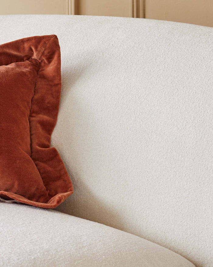 Close-up of a cream sofa with an auburn velvet pillow. A stylish and comfortable addition to any living space.