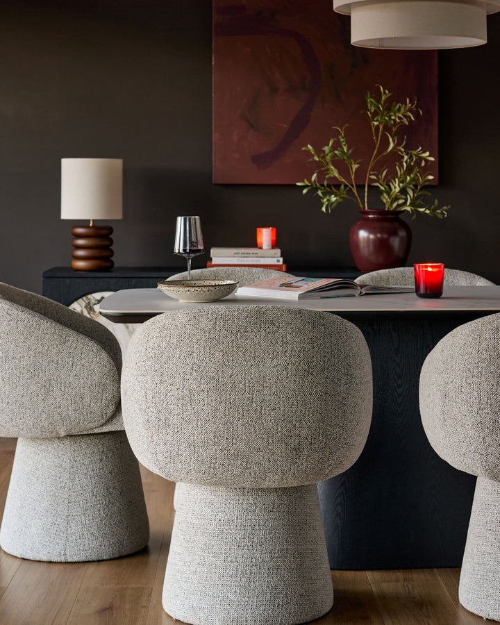 Darcy swivel dining chair in grey fabric with rounded mushroom-shaped design, shown at dining table.