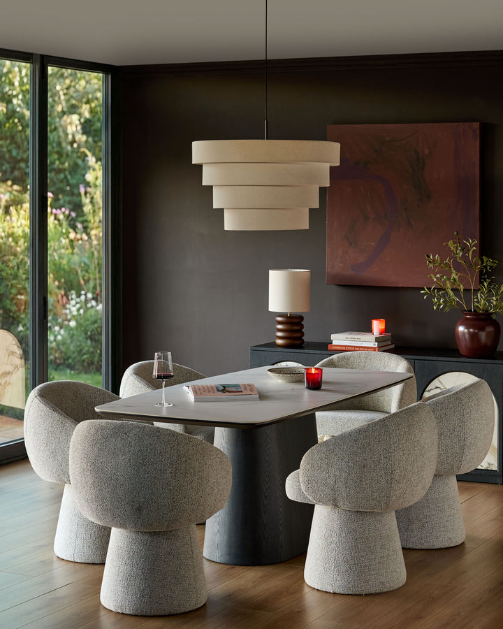 Darcy swivel dining chair in grey fabric, shown in a modern dining room setting around a table with matching chairs.