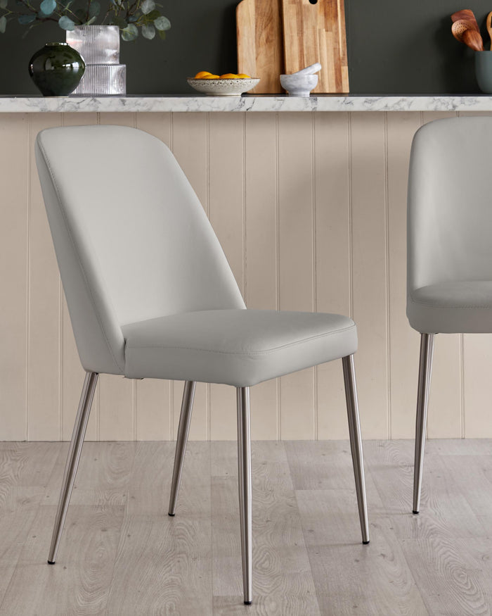 Stylish light grey dining chairs with sleek metal legs, perfect for a modern kitchen or dining space.