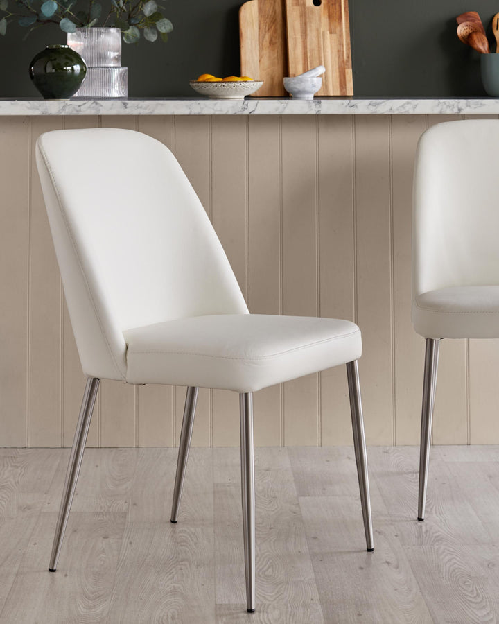 Close up of white faux leather dining chairs with sleek, silver metal legs in a kitchen setting.