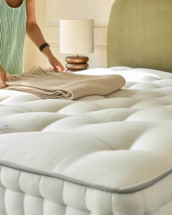 A cosy bedroom scene with a stylish mattress and a striped top. A modern bedside lamp adds to the ambience.