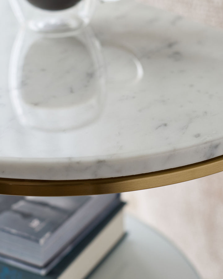 White marble demi-side table with brass trim detail, angled view showing round tabletop and metal base accent.