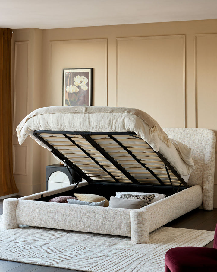 Deven king-size ottoman bed in natural fabric with hydraulic lift mechanism open, showing interior storage compartment.