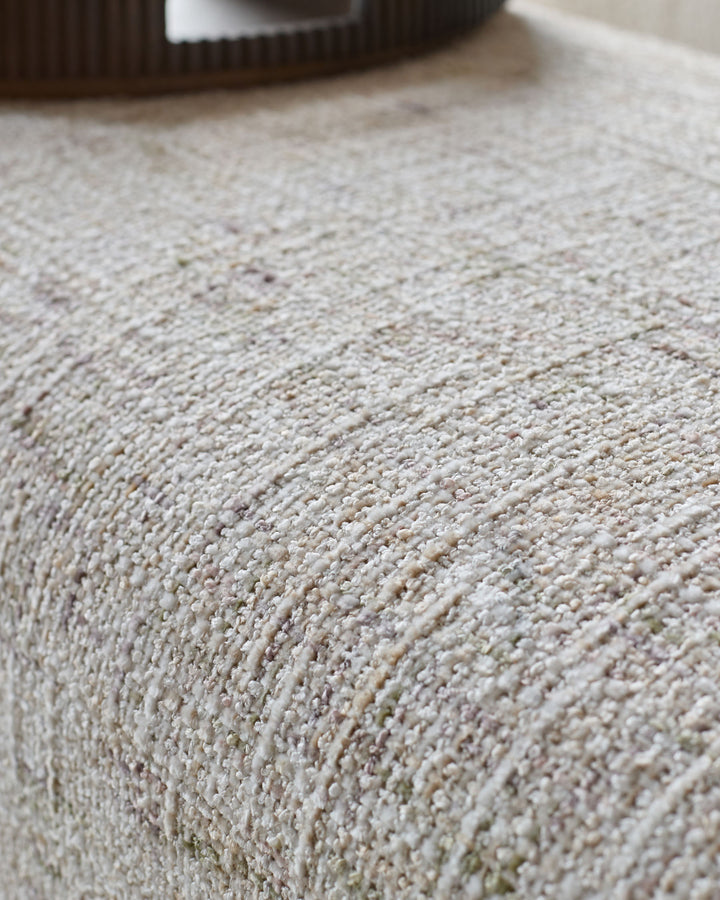Close-up of natural beige textured fabric on Deven bench, showing woven surface detail.