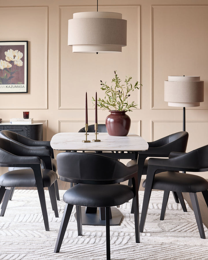 Dylan dining chair in black leather, shown in a modern dining room setting around a marble table.