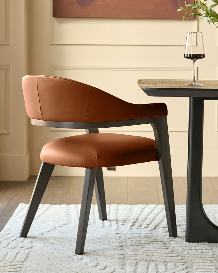 Dylan dining chair in tan leather with black wooden legs, shown at a table with a wine glass and plant.