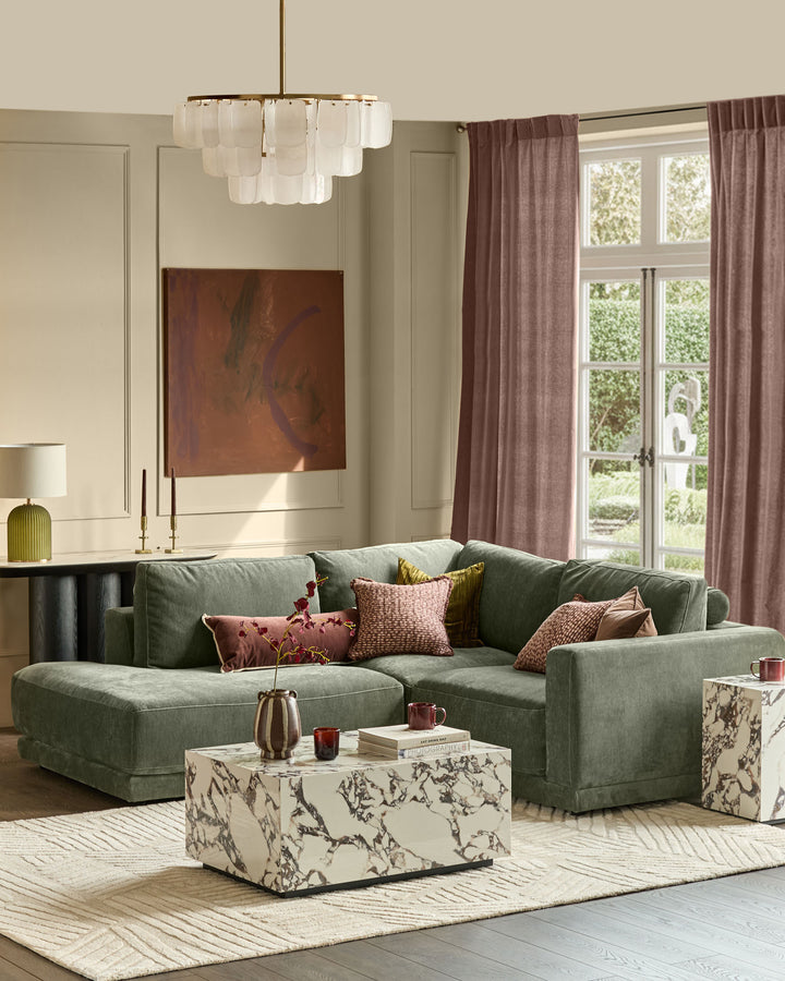 Dark green fabric left-facing small chaise sofa with rolled arms in a contemporary living room setting.