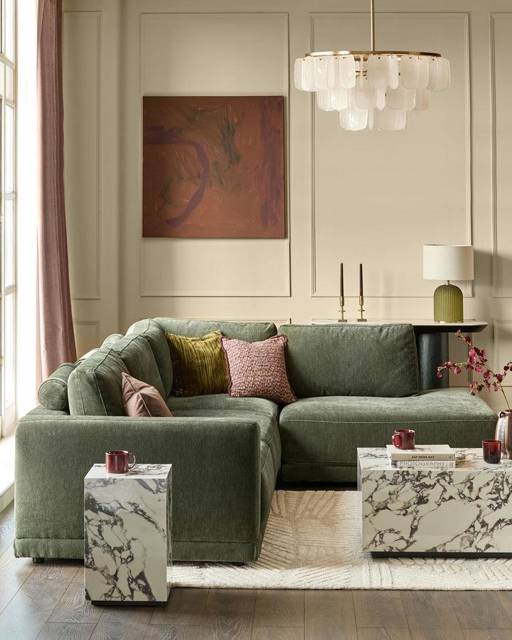 Eden right-facing large chaise sofa in dark green fabric, displayed in a styled living room setting with decorative pillows.