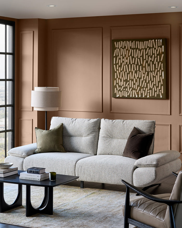 Elio 3-seater sofa in grey fabric with rounded arms, displayed in a warm brown living room setting.