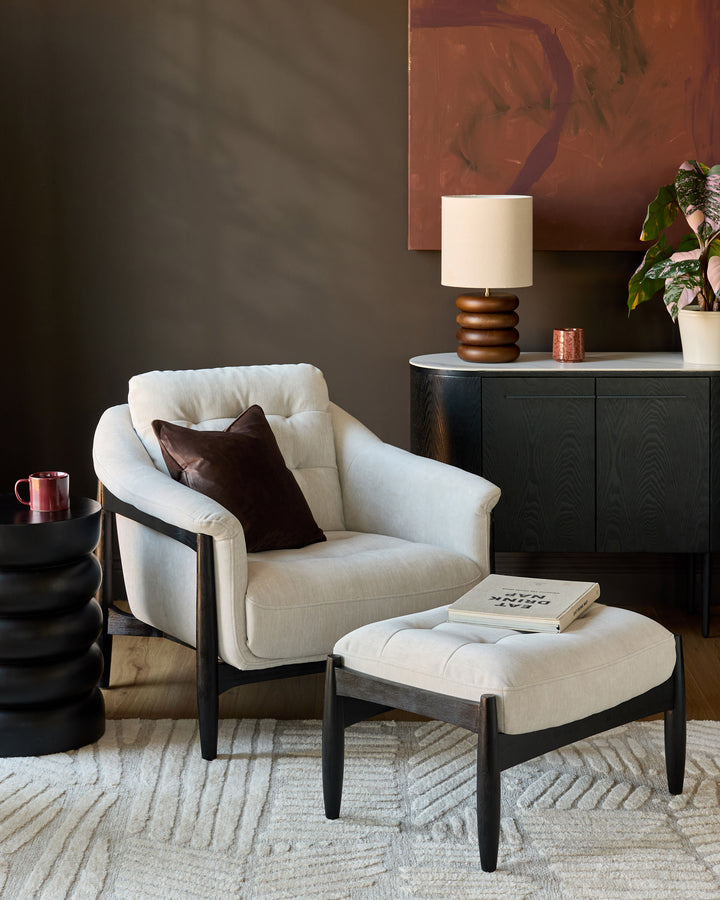Cream textured rug with soft finish, displayed in modern living room setting beneath white chair and ottoman.