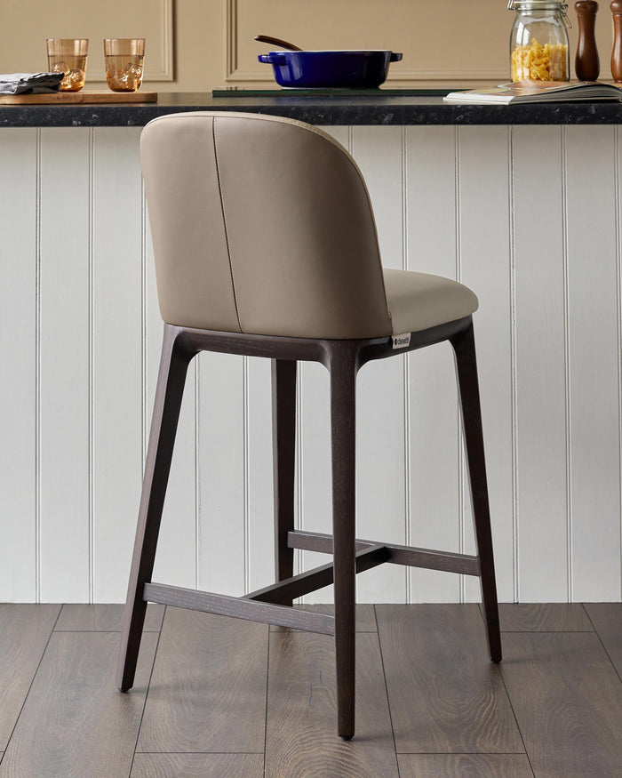 Upholstered bar stool with dark wood frame. Ideal for kitchen islands and bars.