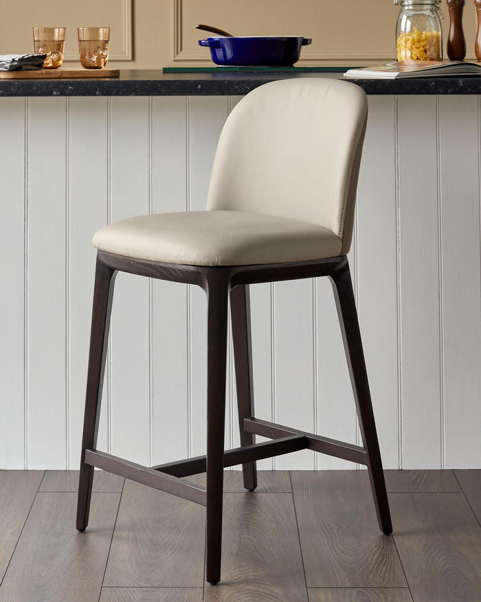 Elegant bar stool with dark wood frame and cream leather seat, perfect for a stylish kitchen or bar area.
