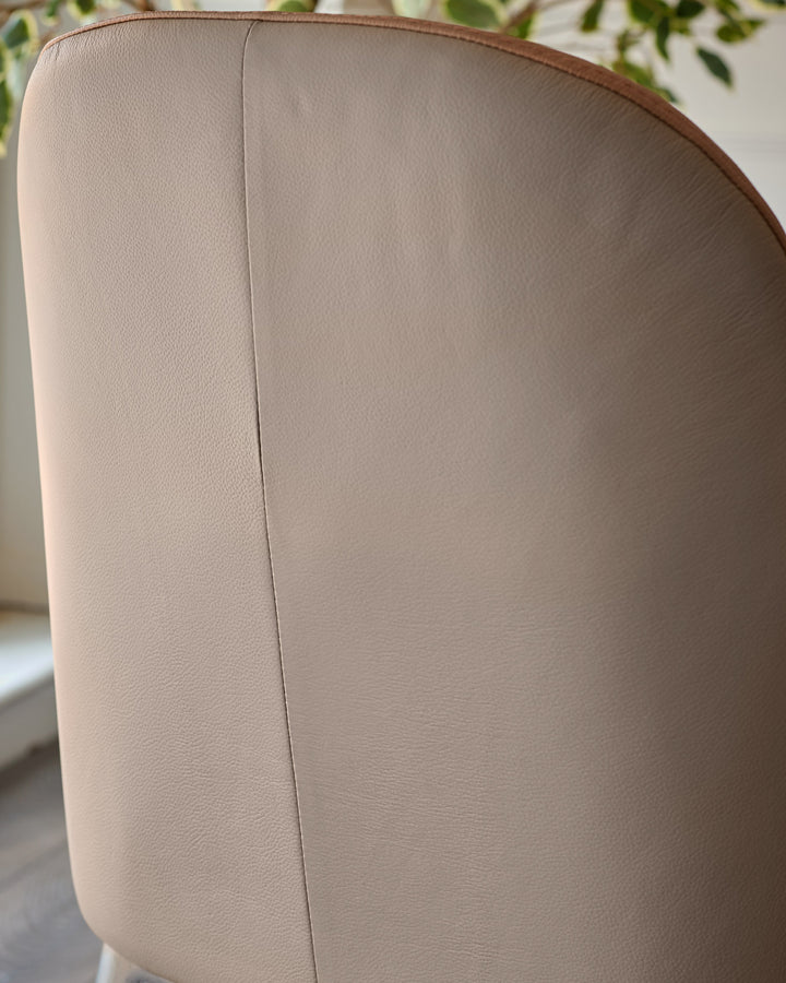 Emerson dining chair in tan leather, showing curved backrest detail and stitching from rear angle view.