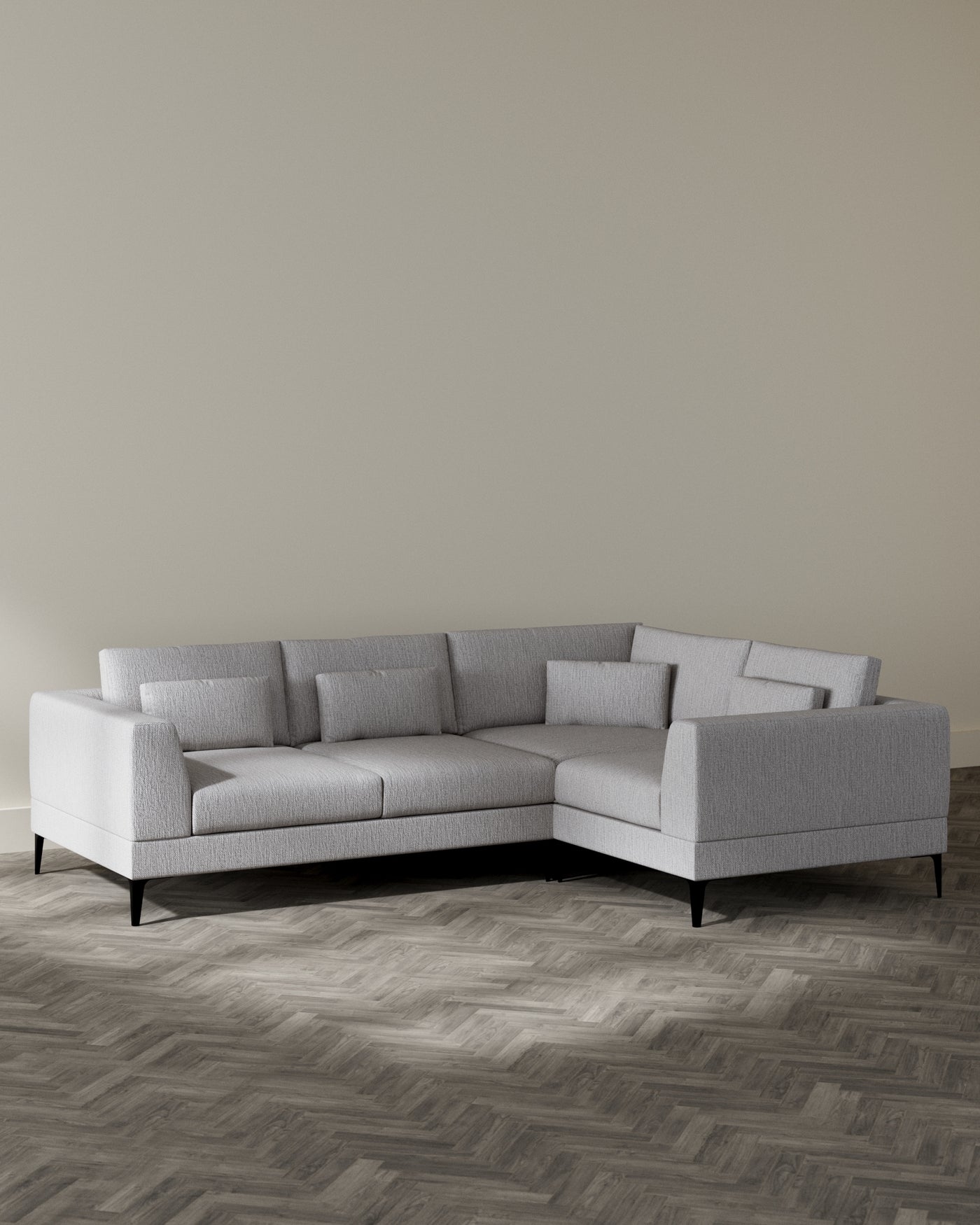 A modern light grey sectional sofa with clean lines, featuring a left-facing chaise lounge, cushions, and slim, dark wooden legs, set in a minimalist room with herringbone parquet flooring.