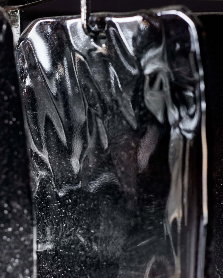 A reflective, textured piece of furniture with a metallic sheen, set against a dark, speckled background.