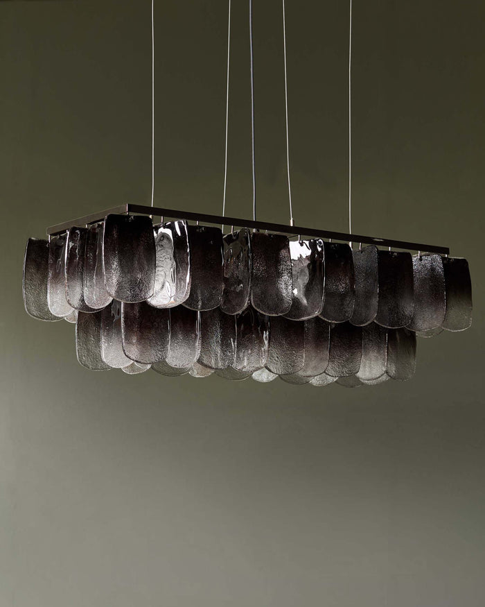 A rectangular chandelier with textural glass elements, suspended by slim cables, adds a touch of modern elegance.