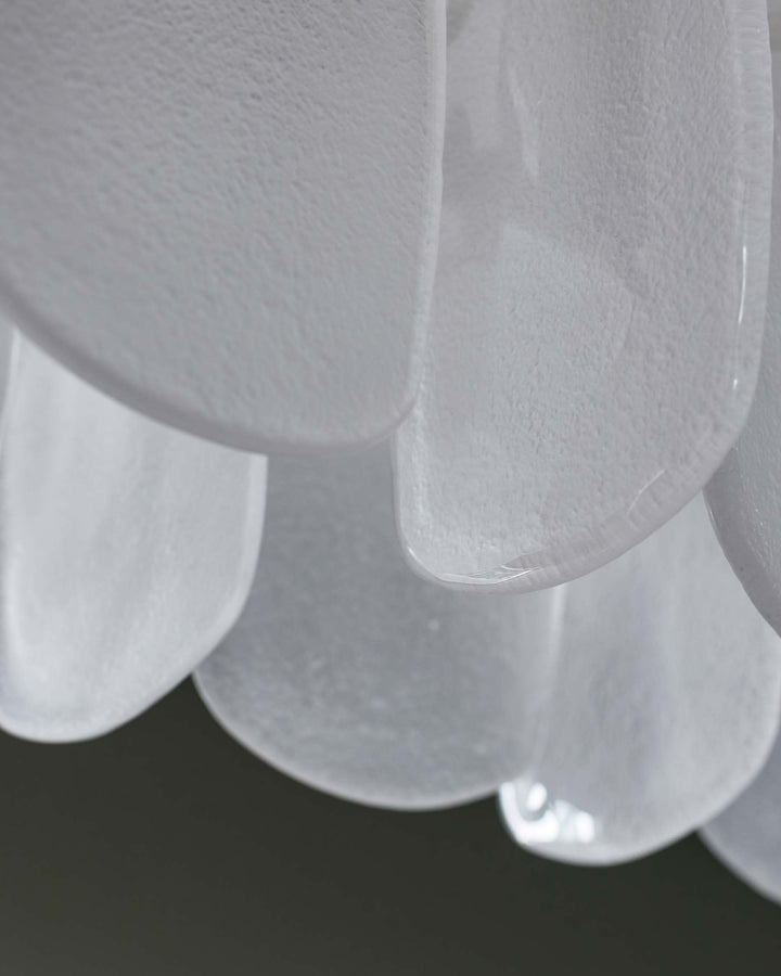 Close-up of layered, textured white glass light fixture, creating a soft, ethereal aesthetic.