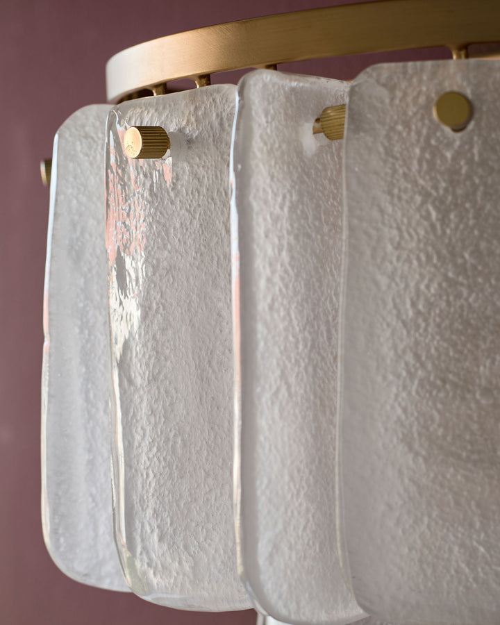 Estelle wall light with brass fixture and white textured glass panels against pink background.