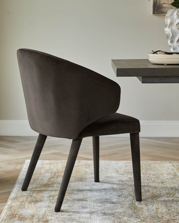 Elegant, dark brown dining chair with a curved back and slim legs, paired with a wooden dining table.
