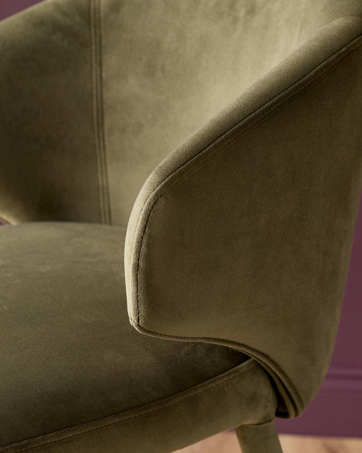 Ethan bar stool in olive green velvet, close-up detail of curved armrest and stitching.